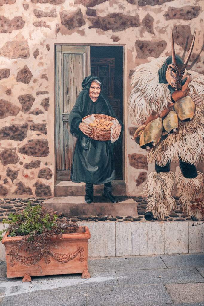 Murales in un paese della Barbagia rappresentante una donna anziana e la maschera sarda mammuthones