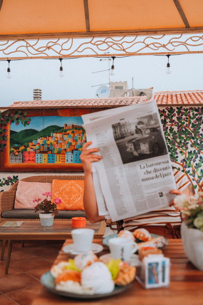 Ragazza legge il giornale in una terrazza a Bosa